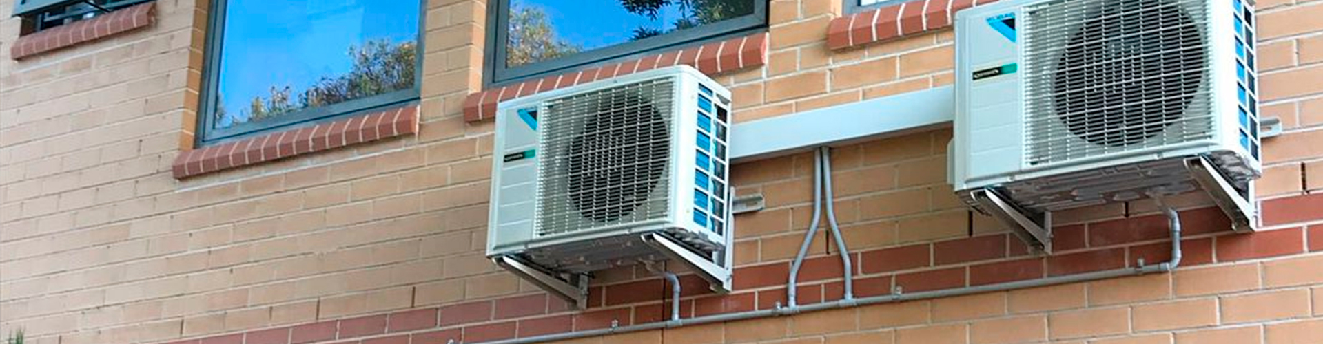 Wall-mounted outdoor air conditioning units on a brick building exterior