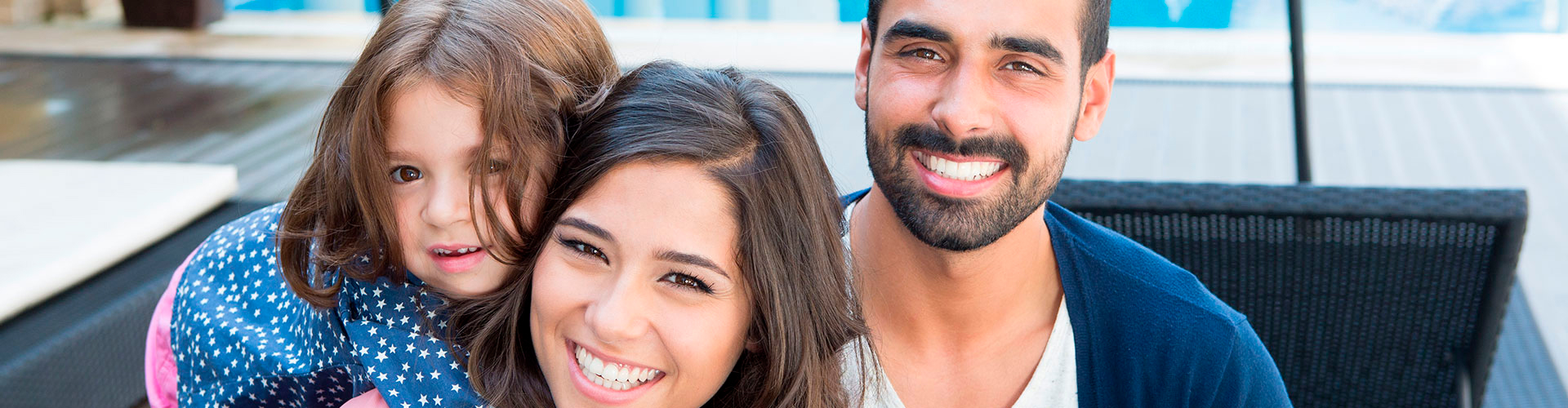 Smiling child, woman, and bearded man sitting together outdoors