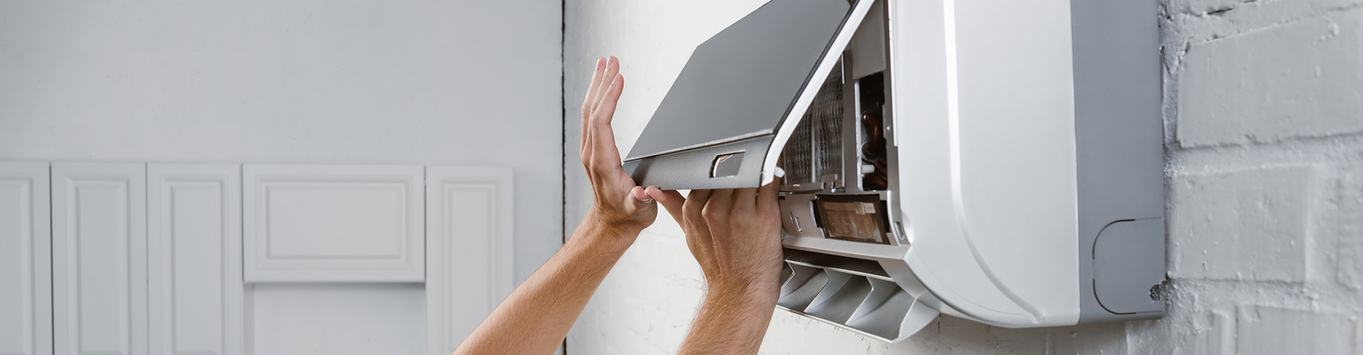 Arms opening a wall-mounted air conditioning unit for maintenance