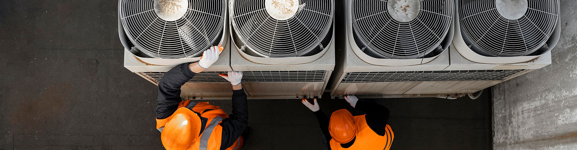 Two technicians in safety vests inspecting rooftop water cooled package unit fans