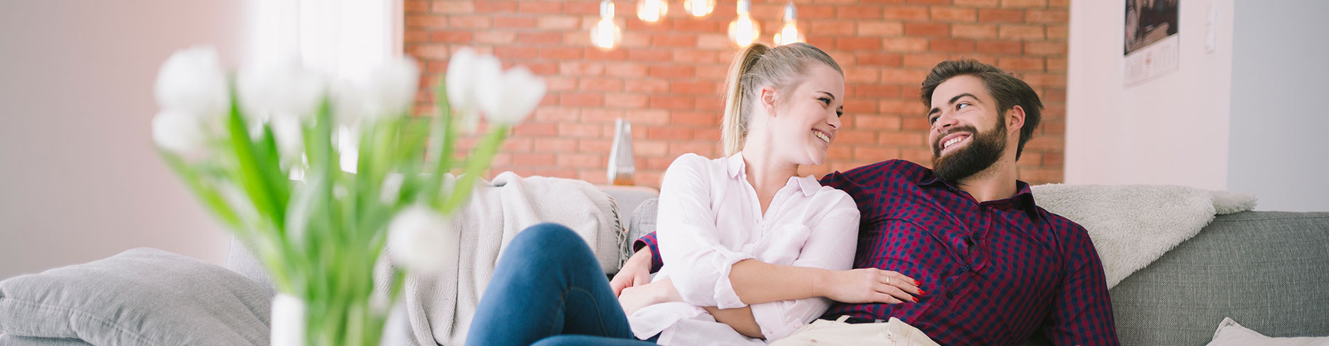 Happy couple laughing together on a sofa at home, relaxed after emergency repair service
