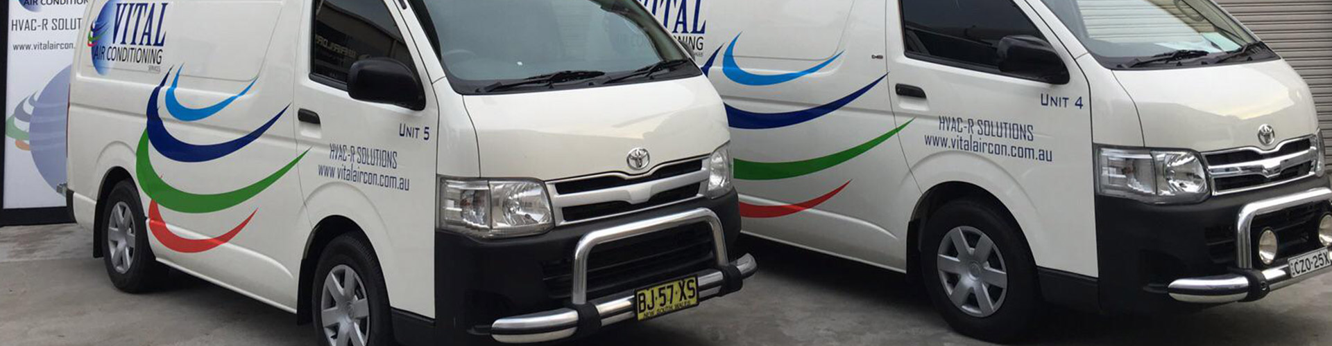 Two white Toyota Hiace vans branded with Vital Air Conditioning HVAC-R Solutions logos parked outdoors