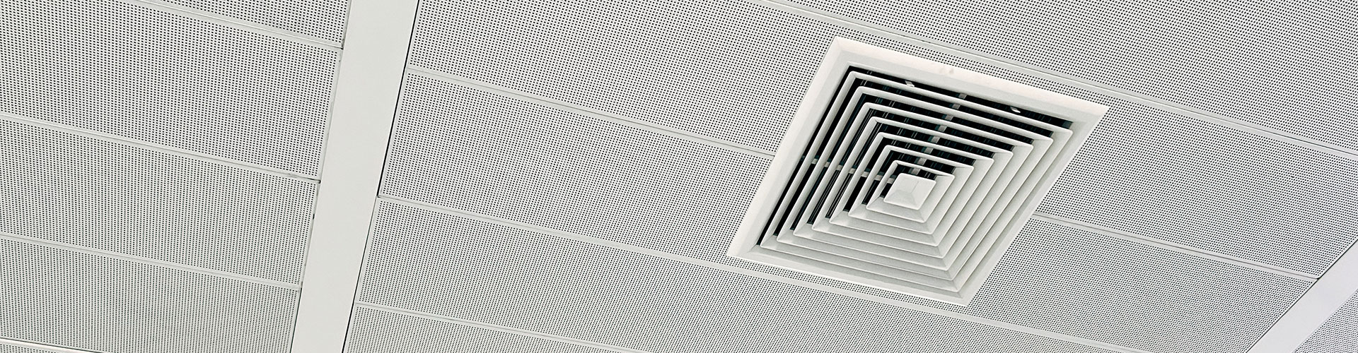 Square HVAC diffuser vent on a perforated white suspended ceiling in a commercial building