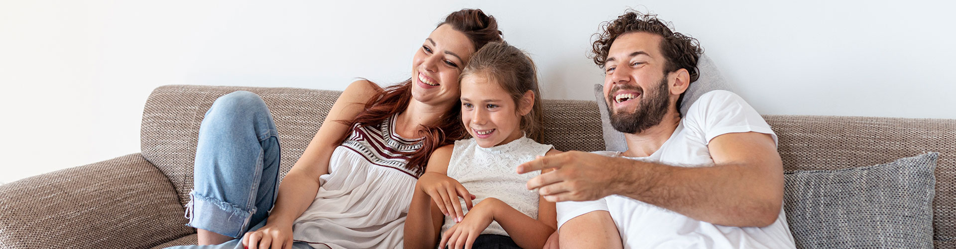 Family laughing together on a sofa at home, relaxed and smiling