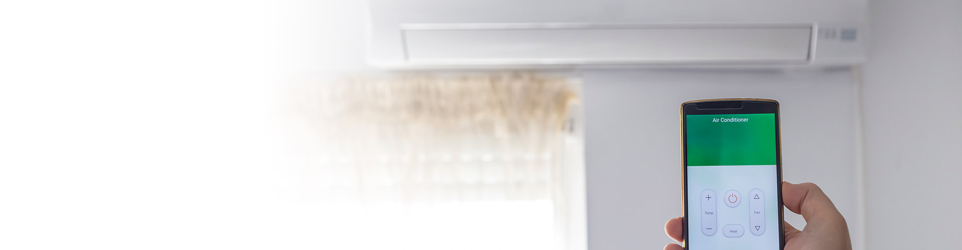 Hand holding a smartphone with an Air Conditioner app controlling a wall-mounted AC unit via WiFi