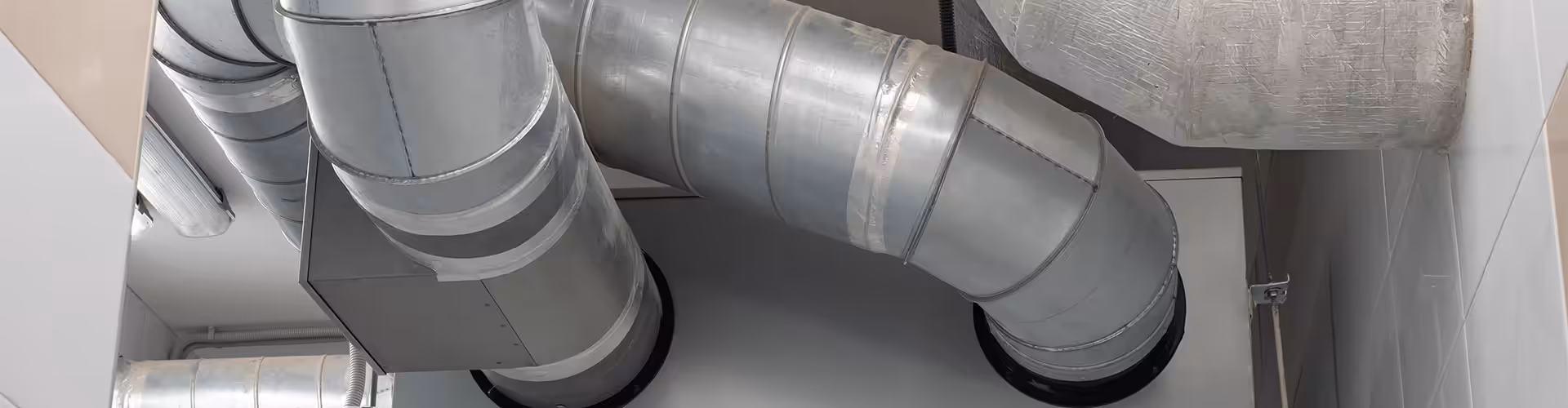 Close-up of ducted air conditioning pipework with metal ducts and joint connectors in a ceiling cavity