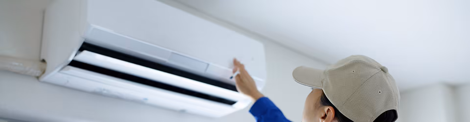 Technician inspecting an open wall-mounted air conditioning unit as a sign it needs repair