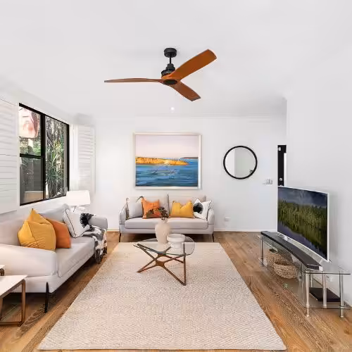 Living room with black ceiling fan, gray sofas, and area rug for home air conditioning comfort