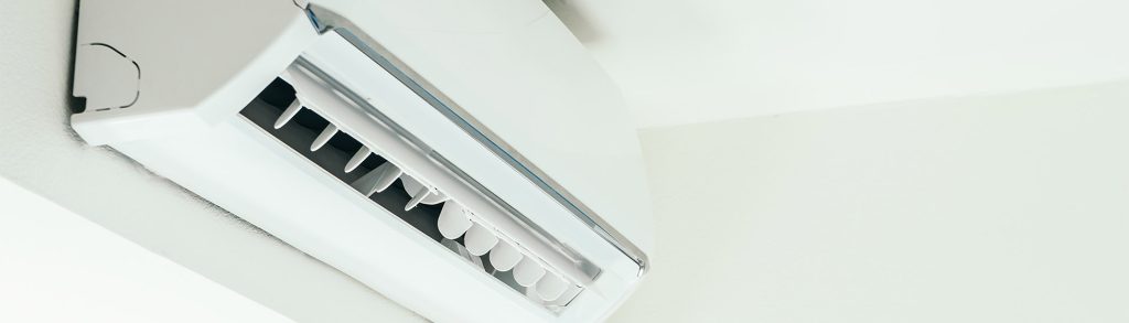 White wall-mounted split air conditioning unit with open vent panel near ceiling, comparing Samsung vs Mitsubishi models