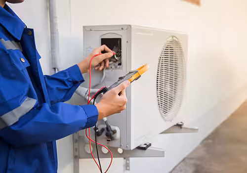 Aircon repairer using a multimeter to test wiring inside an outdoor air conditioning condenser unit