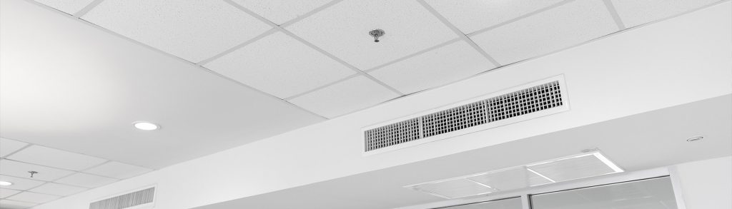 Ceiling-mounted ducted air conditioning vent with slatted grille in a commercial interior