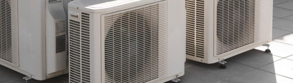 Three white outdoor air conditioner condenser units on a rooftop, related to air conditioner RA filter replacement