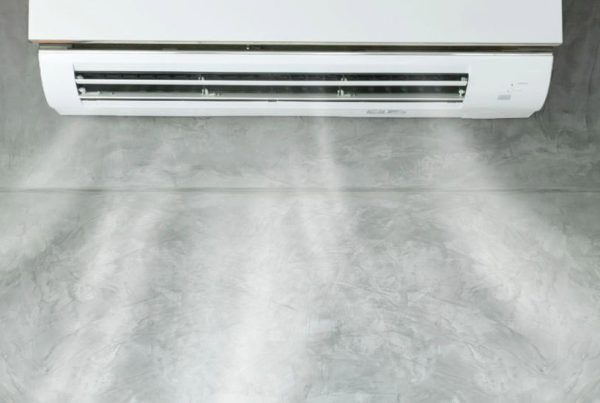 Wall-mounted split air conditioner blowing cool air for indoor humidity control on a concrete wall