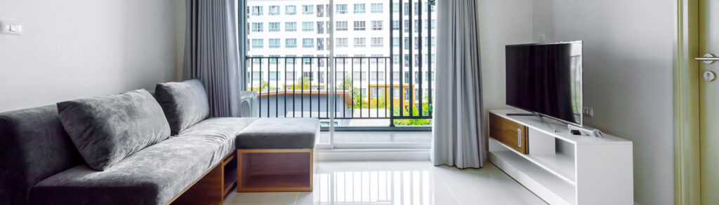 Modern gray living room with sofa, glass balcony door, and TV console for customised air conditioning comfort