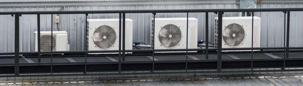 Row of four outdoor aircon condenser units mounted on a rooftop platform to help prevent aircon unit from freezing up