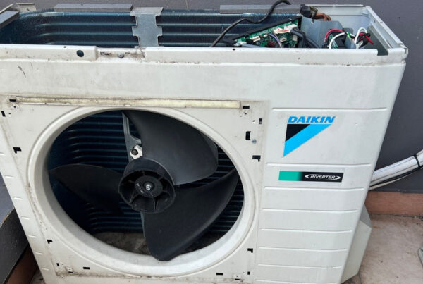 Daikin Inverter air conditioning condenser with cover removed, showing fan, coils, and wiring needing service