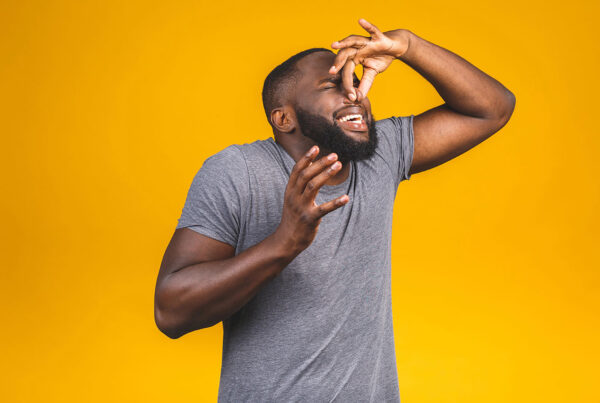 Man pinching his nose in disgust, reacting to a bad smell like a musty air conditioner odor