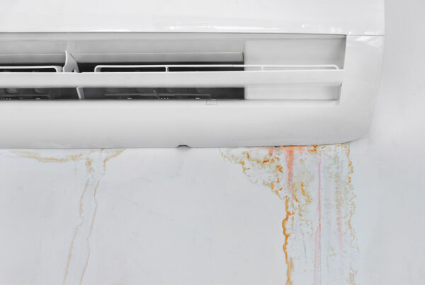 White air conditioner unit with rust-colored water stains leaking down the wall below it